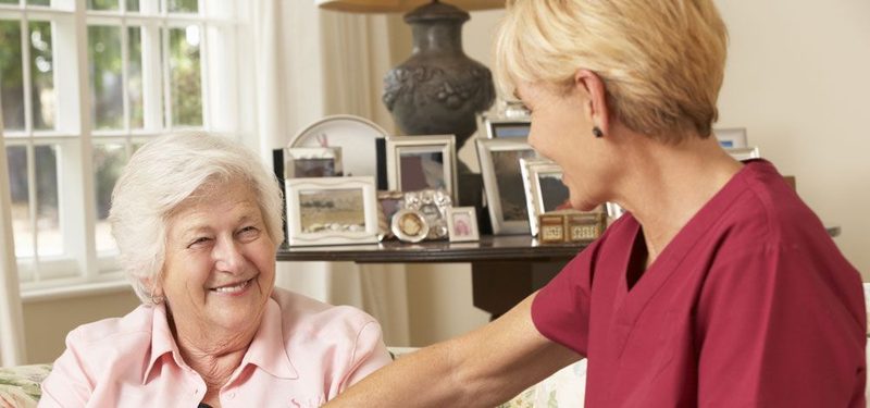 A carer serving a meal to an older woman at home